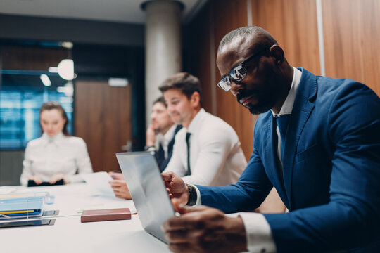 African american black man businessman sitting at table working laptop on office team people background