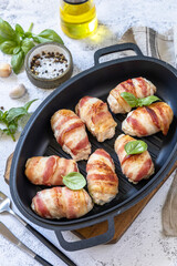 A festive dish. Baked chicken fillet with ricotta in bacon on a stone table top.