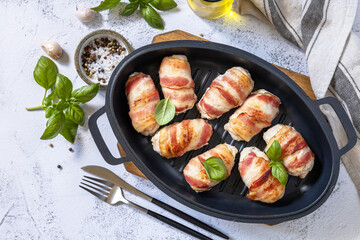A festive dish. Baked chicken fillet with ricotta in bacon on a stone table top. Top view flat lay background.