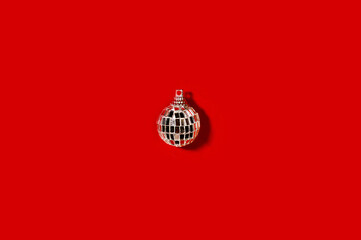 Silver Christmas disco ball bauble on red background. Minimal New year party concept. Flat lay.