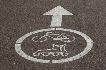 Fototapeta premium Arrow and sign Bike and Roller skates painted on the asphalt. Sidewalk for sportsmen. White road markings on pavement. Top view