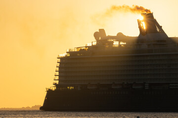 Silhouette of a cruise ship stern in golden morning sun. 