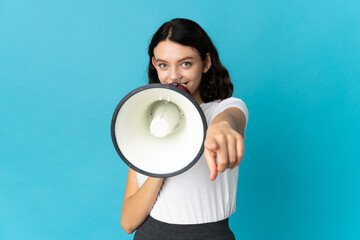 Teenager Ukrainian girl isolated on white background shouting through a megaphone to announce something while pointing to the front