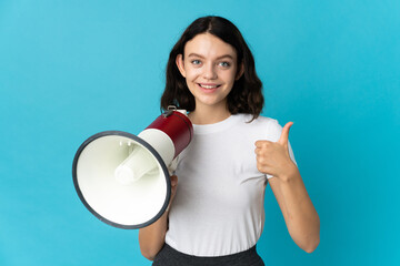 Teenager Ukrainian girl isolated on white background holding a megaphone with thumb up
