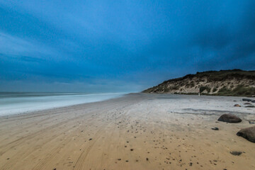 Fototapeta na wymiar Long exposure photo of clouds rolling over a sand beach.