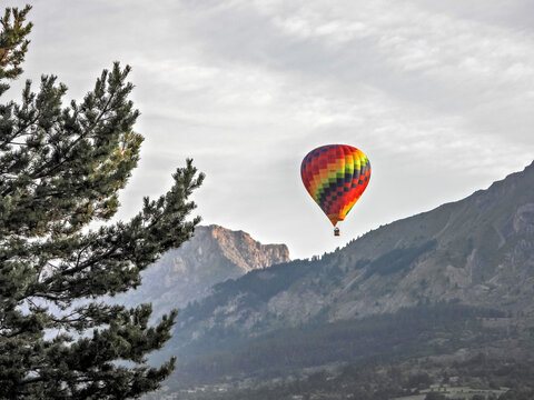 Ballon montgolfi&egrave;re survolant les sommets des Alpes du Sud dans les premi&egrave;res lueurs du soleil