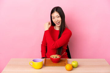 Young Chinese girl  having breakfast in a table celebrating a victory