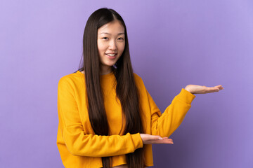 Young Chinese girl over isolated purple background extending hands to the side for inviting to come