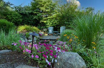 Landscape architecture with pink flowers and ornamental grasses for summer garden with waterfall