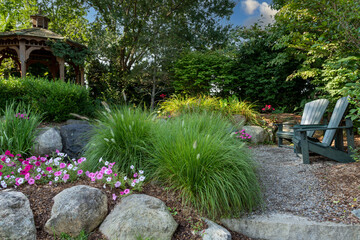 Landscape architecture with pink flowers and ornamental grasses for summer garden with waterfall
