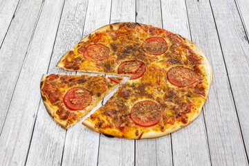 Family caprese pizza with a separate portion with sliced tomato, dried oregano, mozzarella cheese and olive oil