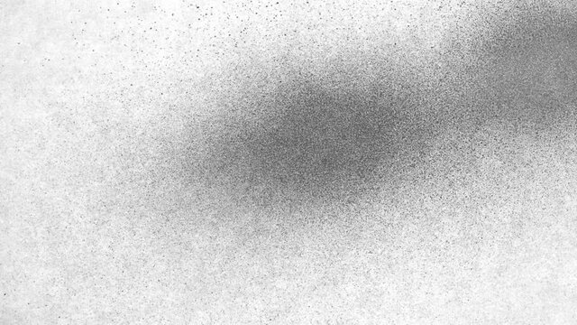 Spraying black paint on white background. Fine spray of ink spreads over surface. Black watercolor paint spraying. Particles of black paint scatter on white pape. Close up. Slow motion ready 59.94fps.
