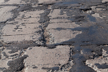 a bad road with poorly repaired potholes and pits