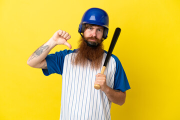 Redhead baseball player man with helmet and bat isolated on yellow background showing thumb down with negative expression