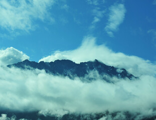 Mountains peak above puffy clouds of Summer in British Columbia Canada