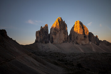 Three peaks of Lavaredo (Drei Zinnen or Tre Cime di Lavaredo) in the Sexten Dolomites National Park during sunrise with light on the peaks