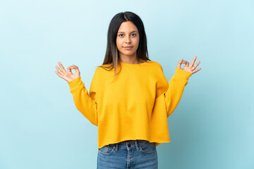 Caucasian girl isolated on blue background in zen pose