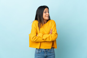 Caucasian girl isolated on blue background making doubts gesture while lifting the shoulders