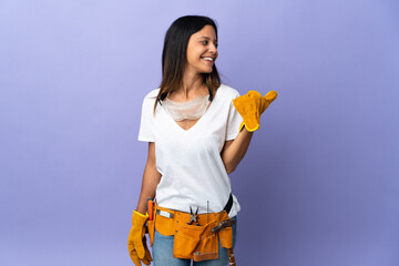 Young electrician woman isolated on purple background pointing to the side to present a product