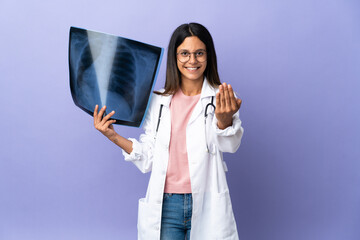 Young doctor woman holding a radiography inviting to come with hand. Happy that you came