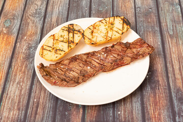 Beef entrails steak cooked on the grill with roasted potato cut in half with sea salt and oregano