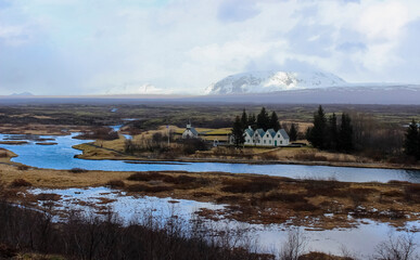 View of a church in Thingvellir, Iceland against a snowcapped mountain backdrop