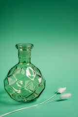 Decorative green glass vase with white plumes on the green surface
