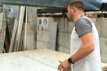 Caucasian man taking measurements to a piece of marble with a tape measure at his workplace