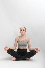 Fototapeta premium Sukhasana. Easy Pose. Young slender woman does yoga and meditates. Girl practices pranayama.