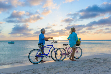 Fototapeta premium Happy senior couple exercising with bicycles on the beach on a sunny day