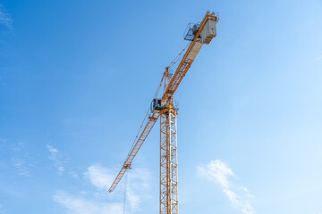 Yellow tower construction crane against blue sky background