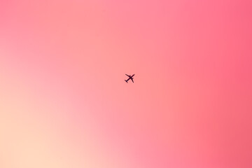 Pink sunset sky with a little plane flying high. Flying to your dreams concept wallpaper. Pink sunset aerial landscape near the airport