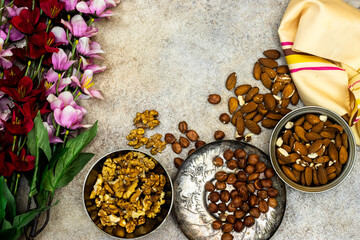 Assortment of nuts in metal bowls hazelnuts, walnuts, almonds with flowers Top view with copy space