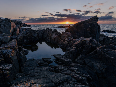 sunset over the sea at kullaberg by &ouml;resund with jagged rocks in the foreground
