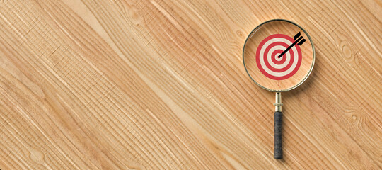 magnifier with a target symbol on wooden background