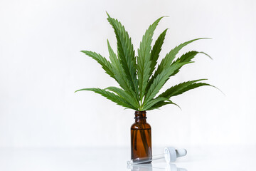 Cannabis leaves in a brown medicinal glass with dropper