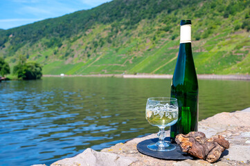 Tasting of white quality riesling wine with view on steep slopes of vineyards overlooking Mosel...