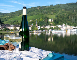 White quality riesling wine served on old bridge across Mosel river with view on old German town in sunny day - obrazy, fototapety, plakaty