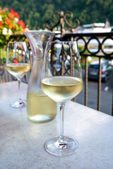 Tasting of white quality riesling wine served on outdoor terrace in Mosel wine region and old German town on background, Germany