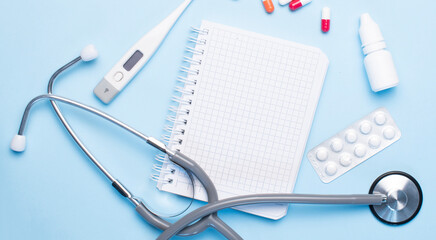 medical concept on a blue background. stethoscope, pills, tablet, notepad, sheet of paper, pen. Medical mask