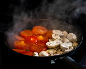 a frying pan cooking tomatoes and mushrooms for breakfast meal