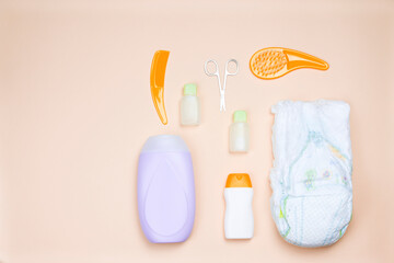 A set of things for baby hygiene. Baby soap, gel, oil, scissors, disposable diaper and combs on a light background. Shower concept.