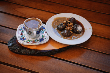 a cup of turkish coffee and fig dessert on the wooden table
