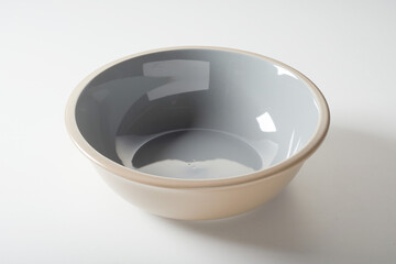 New empty beige ceramic bowl with shiny enamel on white background