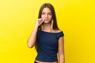 Little caucasian girl isolated on yellow background showing a sign of silence gesture