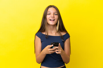 Little caucasian girl isolated on yellow background surprised and sending a message