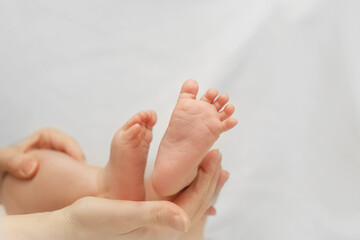 Obraz na płótnie Canvas Newborn Baby Feet in Mother Hand on White Blanket. Concept of Maternity and Child Care. Nursery for Children. Parent Love.
