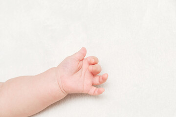 Palm In Fist Of Newborn Baby On White Blanket. Text Space. Child Protection or Adoption