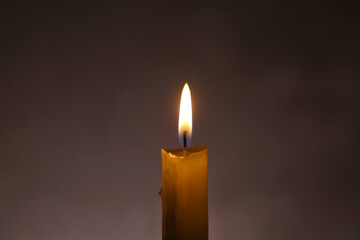 The candle is burning, on a dark background. Macro