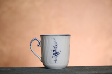 Fototapeta premium A white cup with a pattern stands on a wooden table